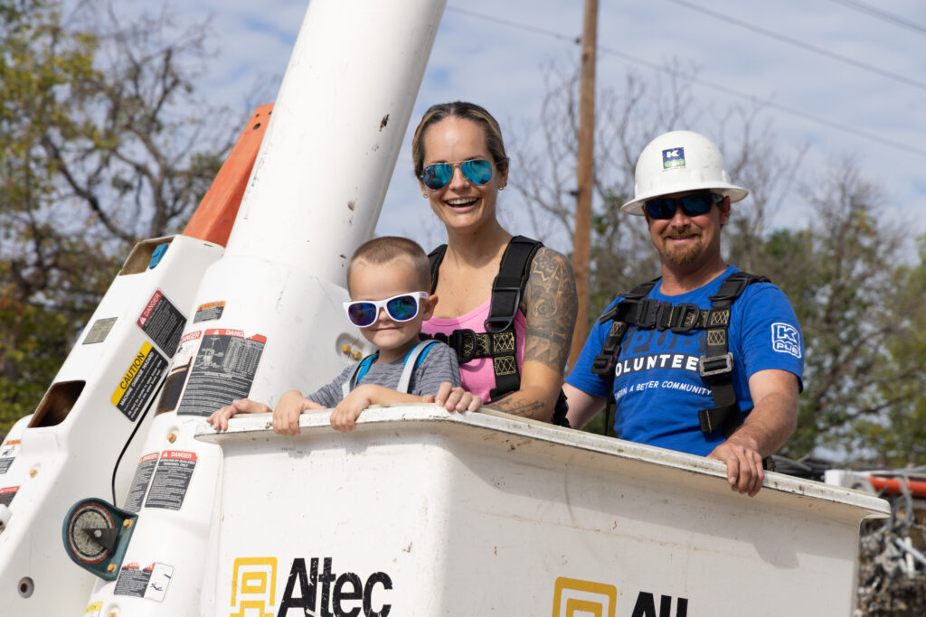 Photo cutline: KPUB crew leader/lineman, Josh Whitworth, with bucket truck ride participants during Public Power Week in 2022.